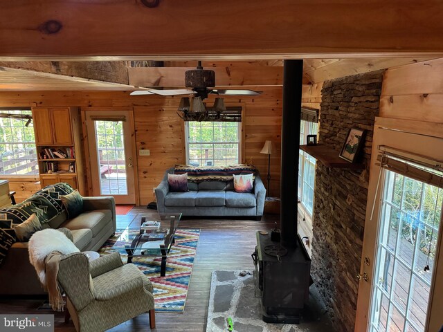 living room featuring wooden walls, hardwood / wood-style floors, ceiling fan, and plenty of natural light