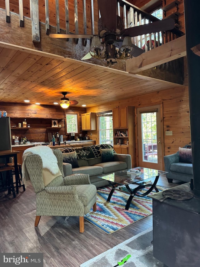 living room with wood-type flooring, wood ceiling, wood walls, and ceiling fan