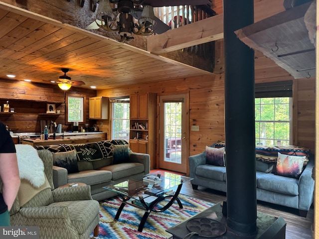 living room with hardwood / wood-style flooring, ceiling fan with notable chandelier, wooden walls, and wood ceiling