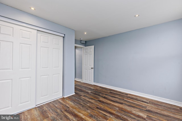 unfurnished bedroom with dark hardwood / wood-style flooring and a closet