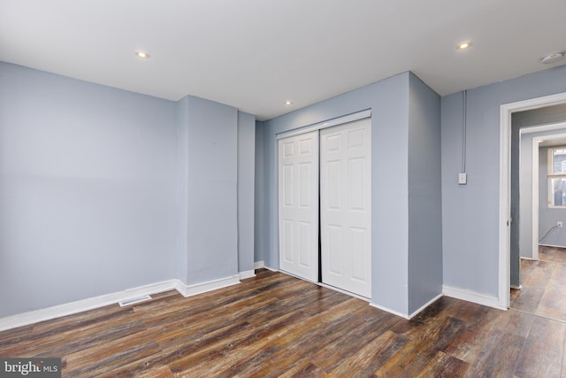 unfurnished bedroom with dark hardwood / wood-style flooring and a closet