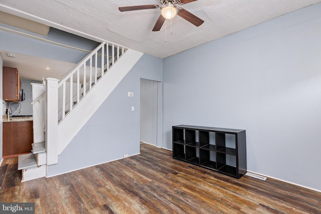 interior space featuring a textured ceiling, ceiling fan, and dark wood-type flooring