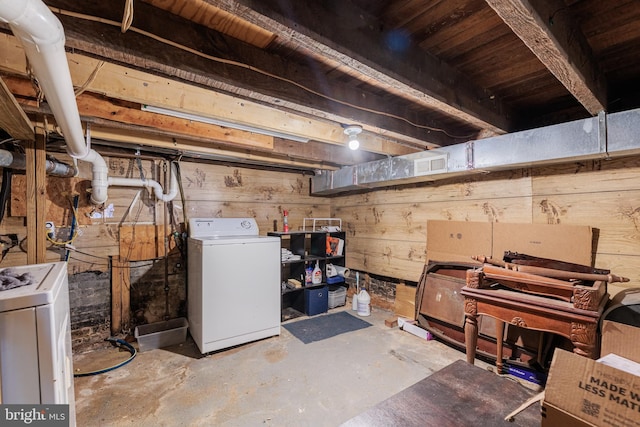 basement with wood walls and washing machine and dryer