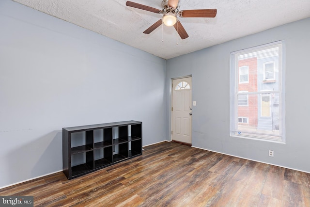 entrance foyer with ceiling fan, dark wood-type flooring, and a textured ceiling