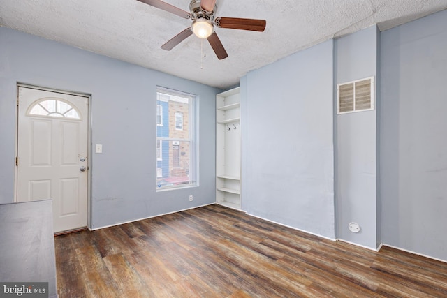 foyer with ceiling fan, a textured ceiling, and dark wood-type flooring