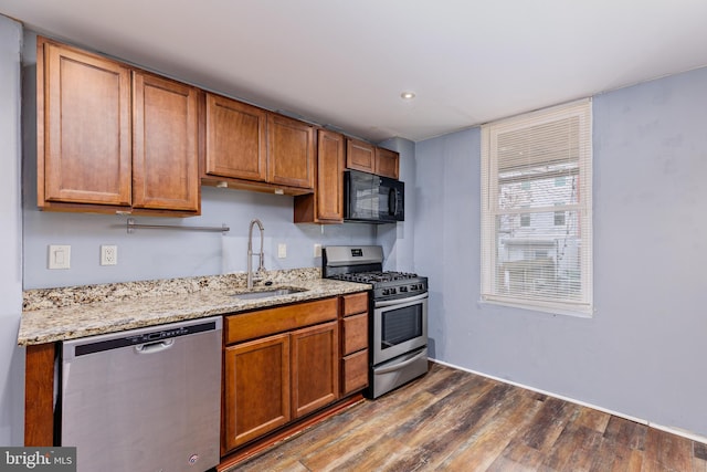 kitchen with light stone counters, dark hardwood / wood-style flooring, sink, and appliances with stainless steel finishes