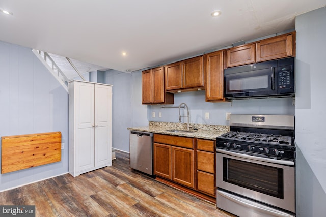 kitchen featuring light stone counters, sink, wood-type flooring, and stainless steel appliances