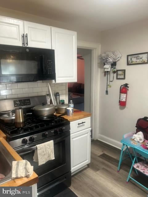 kitchen featuring hardwood / wood-style flooring, stainless steel range with gas cooktop, tasteful backsplash, white cabinetry, and butcher block counters