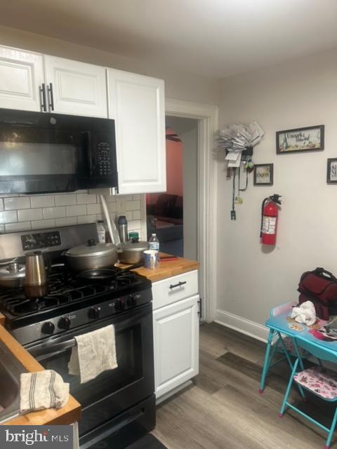 kitchen featuring white cabinets, hardwood / wood-style flooring, stainless steel gas stove, and decorative backsplash