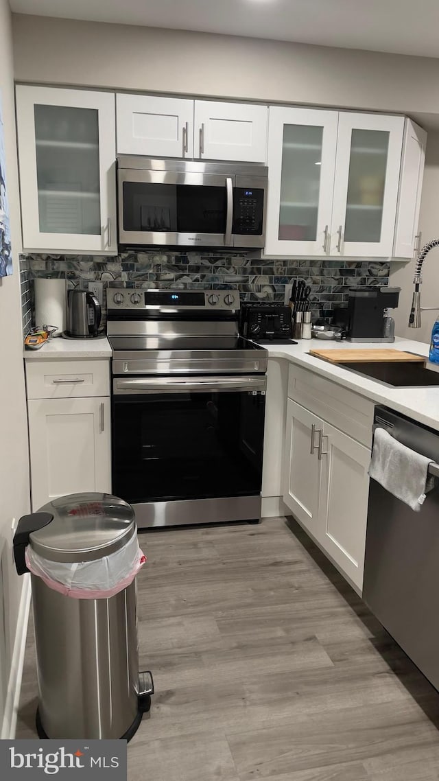 kitchen with white cabinets, stainless steel appliances, sink, and decorative backsplash