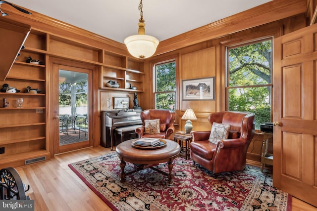 sitting room featuring built in features, light hardwood / wood-style floors, and a healthy amount of sunlight