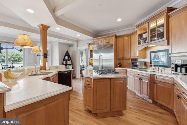 kitchen featuring a kitchen island with sink, sink, decorative columns, light hardwood / wood-style flooring, and stainless steel appliances