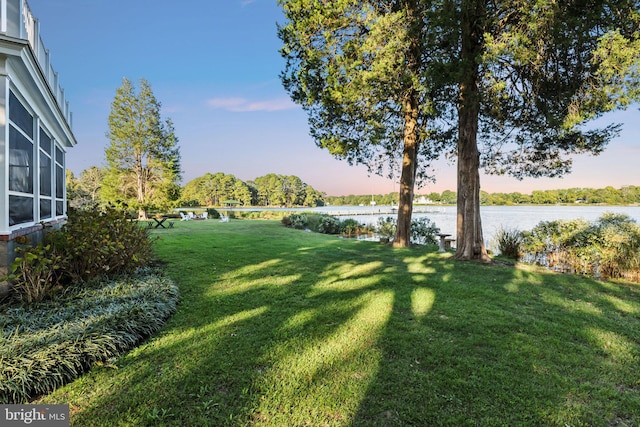 yard at dusk featuring a water view