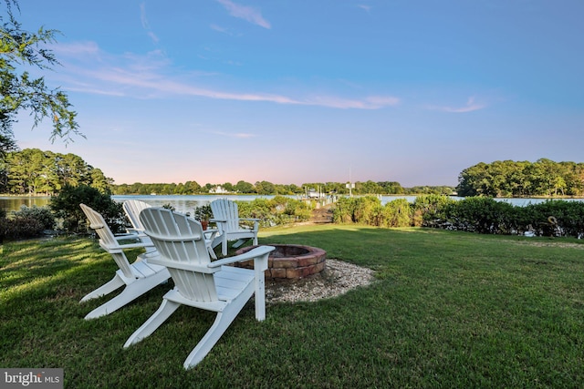 yard at dusk with a water view and a fire pit