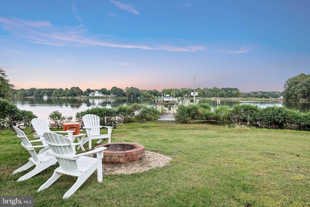 yard at dusk featuring a water view and an outdoor fire pit