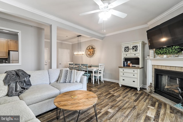 living room with a tiled fireplace, crown molding, dark hardwood / wood-style flooring, and ceiling fan