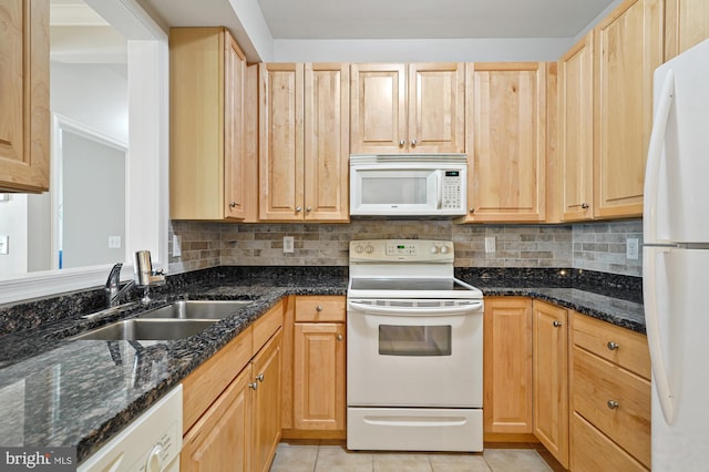 kitchen featuring sink, dark stone counters, white appliances, and light tile patterned floors