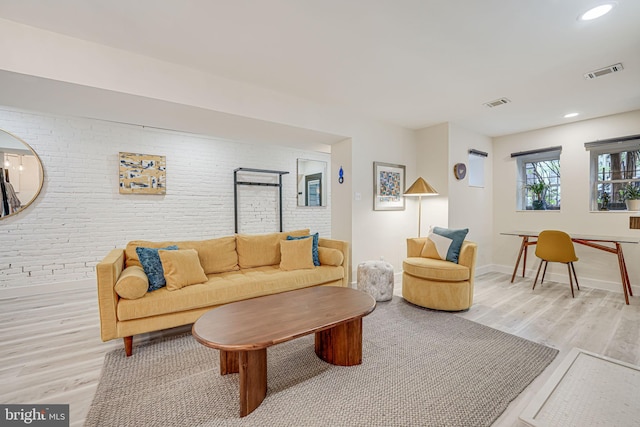 living room featuring brick wall and light wood-type flooring