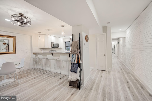 interior space featuring brick wall, light hardwood / wood-style flooring, and sink