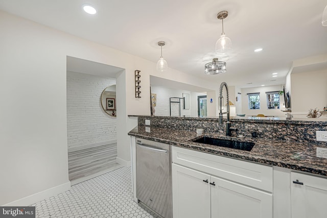 kitchen featuring dark stone countertops, white cabinets, hanging light fixtures, and stainless steel dishwasher