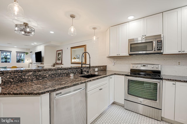 kitchen featuring pendant lighting, sink, white cabinetry, appliances with stainless steel finishes, and dark stone countertops