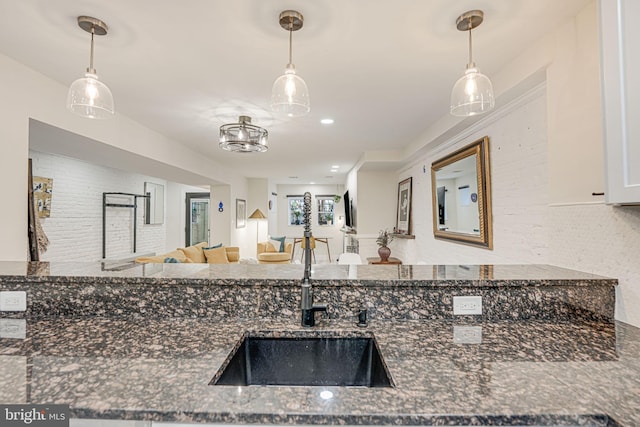 kitchen featuring dark stone countertops, hanging light fixtures, and sink