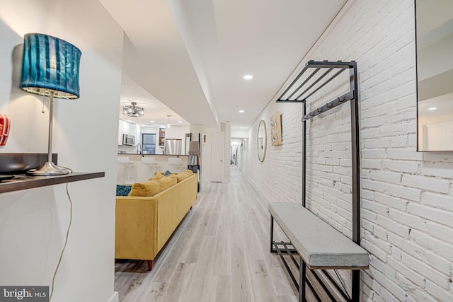 hall with brick wall and light hardwood / wood-style floors