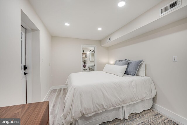 bedroom with connected bathroom and light hardwood / wood-style floors