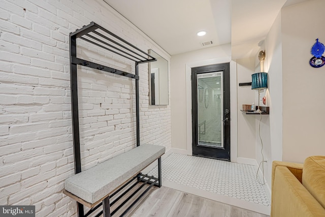 interior space with brick wall and light hardwood / wood-style floors