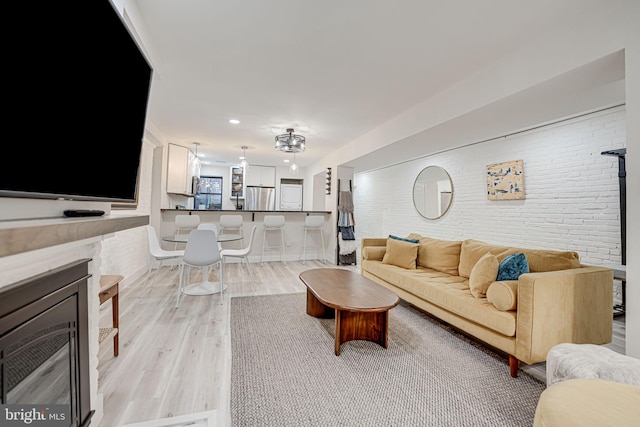 living room with light hardwood / wood-style flooring and brick wall