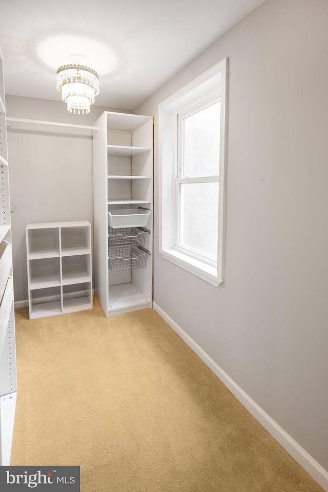 spacious closet featuring light carpet and a notable chandelier