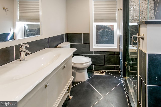 bathroom featuring vanity, toilet, tile walls, tile patterned flooring, and a shower with door