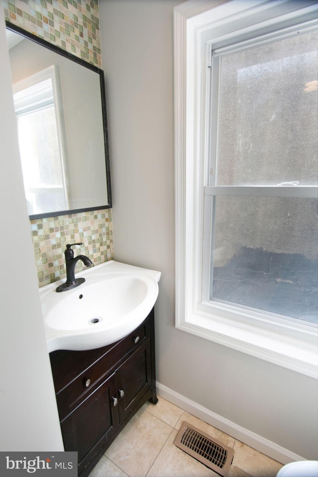 bathroom featuring a healthy amount of sunlight, tile patterned floors, vanity, and tasteful backsplash