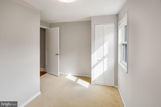 unfurnished bedroom featuring light carpet and a closet