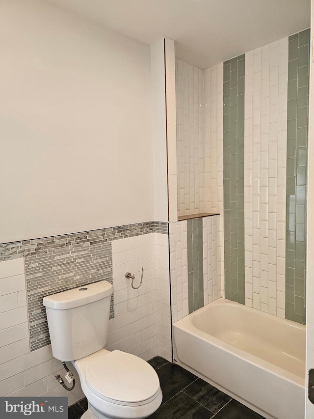 bathroom with shower / bathing tub combination, tile walls, toilet, and tile patterned floors