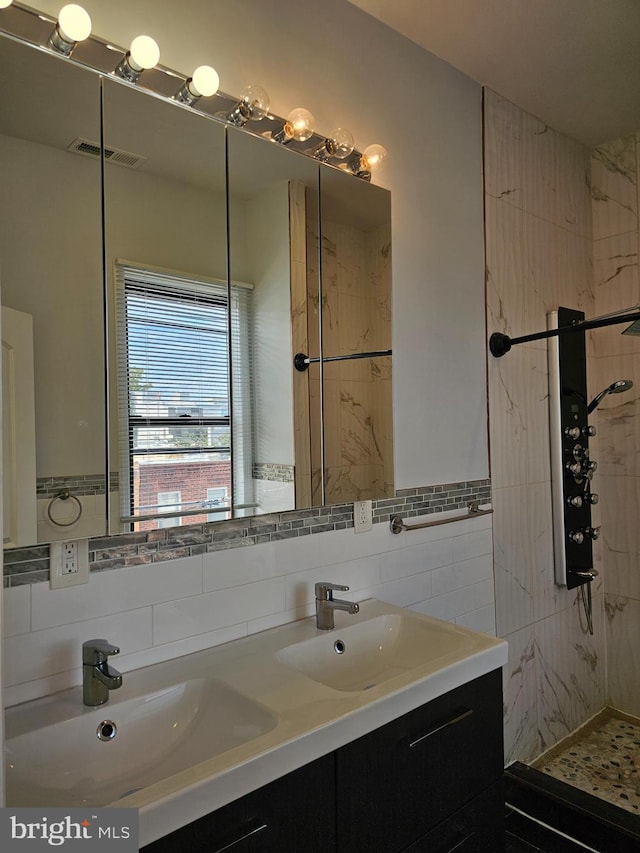 bathroom featuring a tile shower, vanity, and tile walls