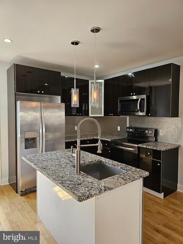 kitchen with light hardwood / wood-style floors, sink, backsplash, appliances with stainless steel finishes, and decorative light fixtures