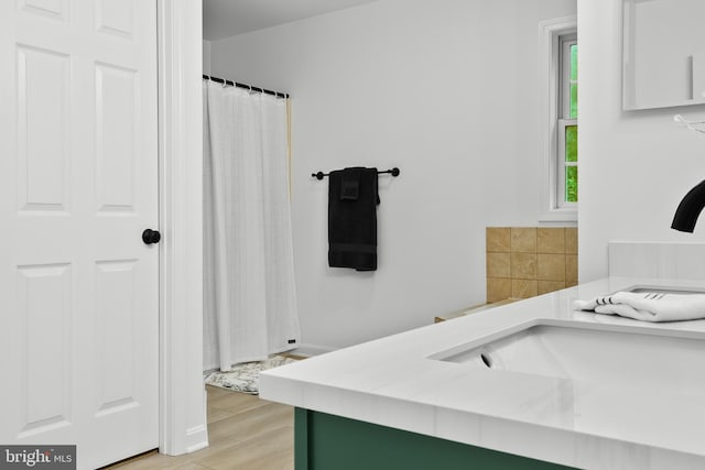 bathroom with walk in shower, vanity, and hardwood / wood-style flooring