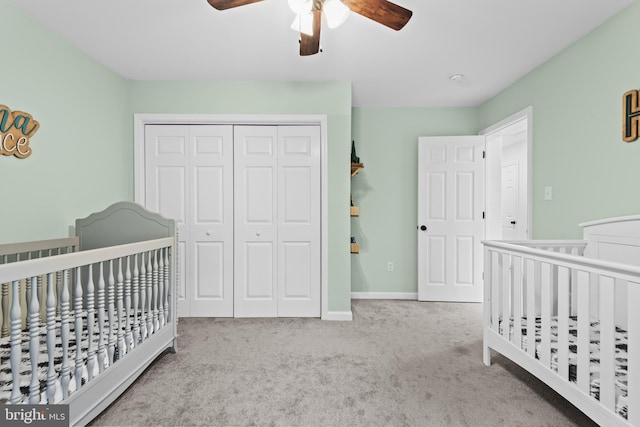 carpeted bedroom with a closet, a nursery area, and ceiling fan