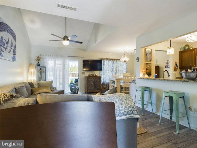 living room with ceiling fan with notable chandelier, lofted ceiling, and dark hardwood / wood-style floors