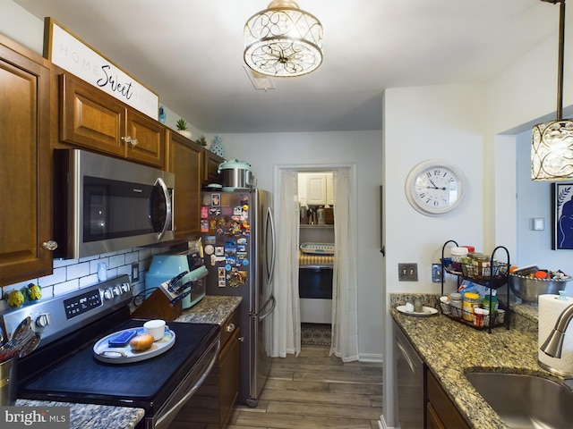 kitchen featuring sink, decorative light fixtures, backsplash, appliances with stainless steel finishes, and dark hardwood / wood-style flooring