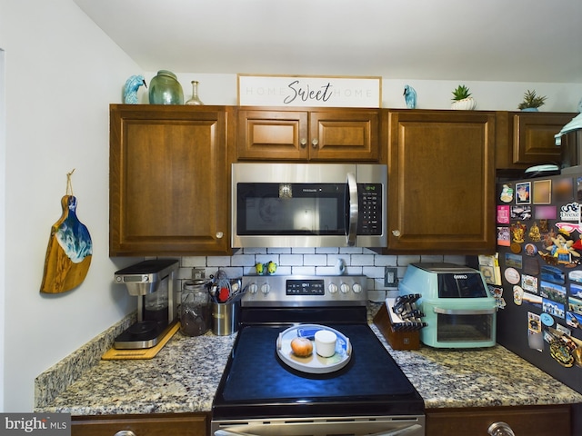 kitchen featuring appliances with stainless steel finishes, dark stone counters, and decorative backsplash