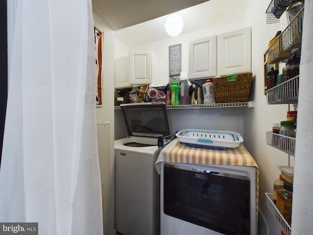 clothes washing area with cabinets and independent washer and dryer