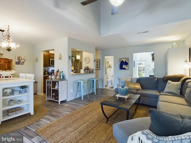 living room with ceiling fan with notable chandelier and dark hardwood / wood-style floors