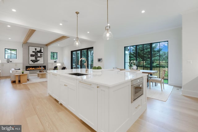 kitchen featuring a wealth of natural light, sink, an island with sink, and a large fireplace