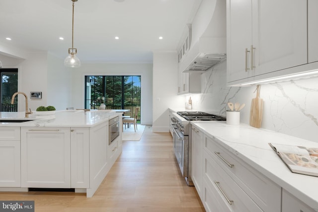 kitchen with sink, white cabinetry, custom range hood, stainless steel appliances, and backsplash