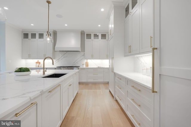 kitchen with white cabinets, premium range hood, and hanging light fixtures