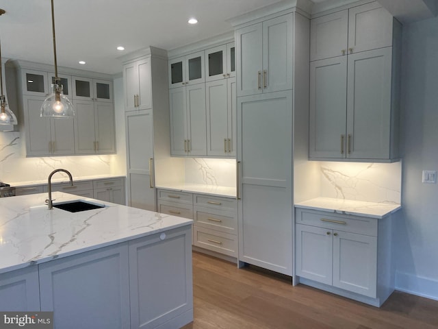 kitchen featuring light stone countertops, decorative light fixtures, backsplash, and dark wood-type flooring