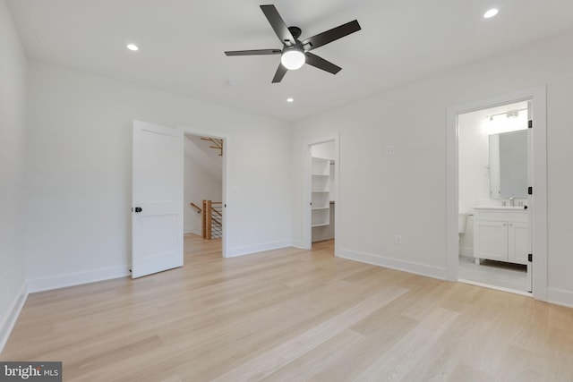 unfurnished bedroom with light wood-type flooring, connected bathroom, ceiling fan, and a walk in closet