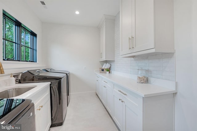 laundry room featuring washer and clothes dryer and cabinets